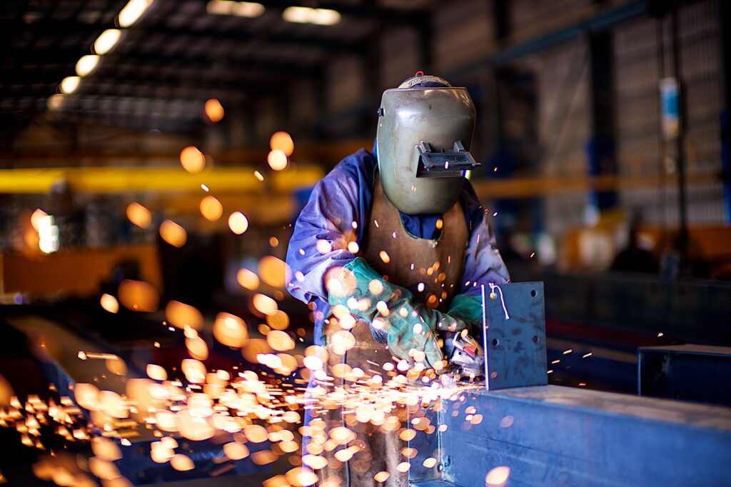 Welder fabricating steel with sparks in an industrial workshop