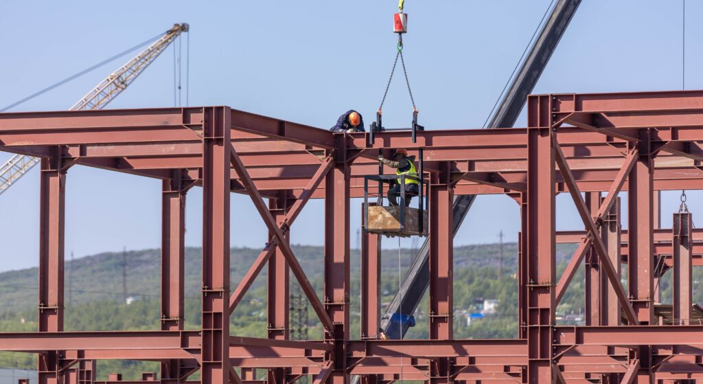 Workers assembling structural steel beams at a construction site